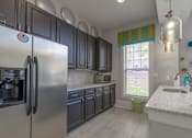 Thumbnail 24 of 48 - A kitchen with a stainless steel refrigerator and black cabinets at Ellicott Grove, Ellicott City, MD 21043