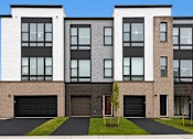 Thumbnail 7 of 8 - A modern two story building with a black garage door.