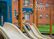 Thumbnail 17 of 18 - a boy is sitting on a slide on a playground at Hamilton Manor Apartments, Hyattsville, 20782