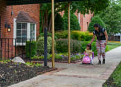 Thumbnail 13 of 18 - a woman pushing a little girl in a pink toy car at Hamilton Manor Apartments, Hyattsville, MD