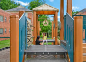 Thumbnail 16 of 18 - a woman and a child sitting on a swing on a playground at Hamilton Manor Apartments, Hyattsville
