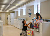 Thumbnail 9 of 18 - two young girls sitting on washing machines in a laundry room at Hamilton Manor Apartments, Hyattsville, MD 20782