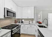 Thumbnail 3 of 18 - Modern kitchen with white cabinets and stainless steel appliances at Park at Winterset Apartments, Owings Mills, MD 21117