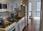 Thumbnail 1 of 8 - A kitchen with white cabinets and a stove top oven.