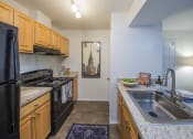 Thumbnail 7 of 35 - a kitchen with wood cabinets and black appliances at Madison at Eden Brook, Maryland, 21046