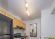 Thumbnail 9 of 35 - a kitchen with a black refrigerator freezer next to a stove top oven at Madison at Eden Brook, Maryland