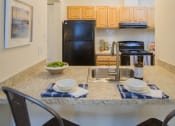 Thumbnail 8 of 35 - a kitchen with a black refrigerator freezer next to a stove top oven at Madison at Eden Brook, Columbia