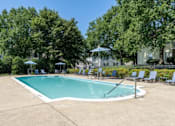 Thumbnail 34 of 56 - A large swimming pool surrounded by trees and chairs at Madison at Eden Brook, 21046