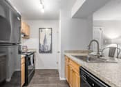 Thumbnail 13 of 56 - A kitchen with a black stove top oven and a black refrigerator at Madison at Eden Brook, 21046