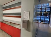 Thumbnail 6 of 8 - A hallway with a red door and a red and white striped wall.