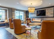 Thumbnail 19 of 84 - A living room with a fireplace and leather chairs at Mira Upper Rock, Maryland, 20850