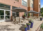 Thumbnail 24 of 24 - A patio with chairs and umbrellas in front of a brick building at Prairie Crossing, Farmers Branch