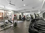 Thumbnail 16 of 24 - A gym with treadmills, elliptical machines, and a fan at Prairie Crossing, Farmers Branch, Texas