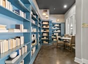 Thumbnail 11 of 24 - A room with blue bookshelves filled with books and a table with chairs at Prairie Crossing, Farmers Branch, TX