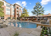 Thumbnail 19 of 24 - A large pool surrounded by a patio area with a building in the background at Prairie Crossing, Farmers Branch, Texas
