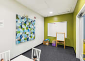 Thumbnail 27 of 54 - a classroom with a whiteboard and a painting on the wall at Villages at Morgan Metro, Landover