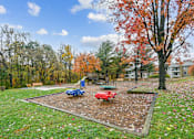Thumbnail 40 of 45 - A playground with a blue slide and a red slide surrounded by trees  at Poplar Glen Apartments, Columbia, MD, 21044.