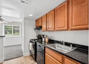 Thumbnail 4 of 40 - Kitchen with black appliances and wood cabinetry at The Brook At Columbia Apartments, Columbia, 21044