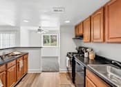 Thumbnail 3 of 40 - Galley kitchen with wood cabinets and black countertops at The Brook At Columbia Apartments, Columbia, Maryland