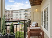 Thumbnail 11 of 49 - A balcony with a table and chairs overlooks a courtyard.