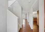 Thumbnail 16 of 54 - a hallway with white walls and a staircase with wood floors at Villages at Morgan Metro, Landover, MD