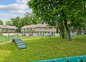 Thumbnail 24 of 40 - Enclosed dog park with agility equipment and benches at The Brook At Columbia Apartments, Columbia, MD 21044