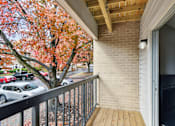 Thumbnail 20 of 45 - A balcony with a wooden floor and a metal railing with a view of a tree with red leaves  at Poplar Glen Apartments, Columbia, MD, 21044.