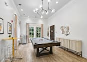 Thumbnail 34 of 45 - A pool table is in the middle of a room with a yellow table and a chandelier  at Poplar Glen Apartments, Columbia, MD, 21044.