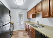 Thumbnail 10 of 45 - A kitchen with a black refrigerator and wooden cabinets  at Poplar Glen Apartments, Columbia, MD, 21044.