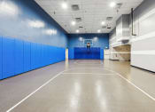 Thumbnail 24 of 54 - a basketball court in a large room with blue walls and a white scoreboard at Villages at Morgan Metro, Landover, Maryland