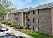 Thumbnail 25 of 40 - Three story brick apartment building with black shutters at The Brook At Columbia Apartments, Columbia, Maryland