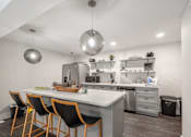 Thumbnail 8 of 46 - A modern kitchen with a white countertop and black chairs.
