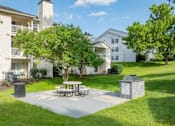 Thumbnail 42 of 46 - A white apartment building with a tree and picnic table in front.
