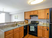 Thumbnail 6 of 65 - A kitchen with wooden cabinets and a black refrigerator.