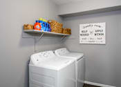 Thumbnail 24 of 65 - A laundry room with a washer and dryer and a sign on the wall.