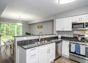 Thumbnail 5 of 65 - A modern kitchen with white cabinets and a granite countertop.