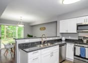 Thumbnail 6 of 81 - A kitchen with white cabinets and a black countertop.