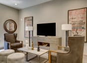 Thumbnail 35 of 54 - a living room with a fireplace and chairs and a television at Villages at Morgan Metro, Landover Maryland