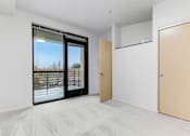 Thumbnail 18 of 26 - A room with a sliding glass door and a wooden door.