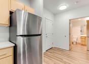 Thumbnail 14 of 26 - A kitchen with a stainless steel refrigerator and wooden cabinets.
