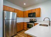Thumbnail 21 of 26 - A kitchen with a stainless steel refrigerator, microwave, oven, and sink.