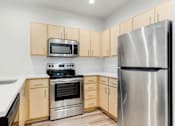 Thumbnail 8 of 26 - A kitchen with a stainless steel refrigerator, microwave, oven, and sink.