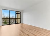 Thumbnail 11 of 26 - A room with a large window and wooden flooring.