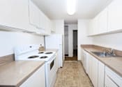 Thumbnail 32 of 47 - A kitchen with white appliances and cabinets.