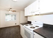 Thumbnail 19 of 47 - A white stove in a kitchen with white cabinets and a ceiling fan.