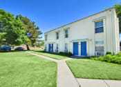Thumbnail 20 of 48 - the exterior of a white building with blue doors and a sidewalk