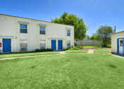 Thumbnail 12 of 48 - a large white building with blue doors and a lawn