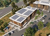 Thumbnail 3 of 9 - A building with solar panels on the roof is surrounded by a parking lot and trees.