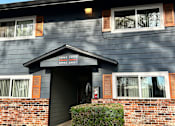 Thumbnail 10 of 47 - A grey building with a black roof and a sign on the front.