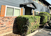 Thumbnail 9 of 47 - A building with a grey facade and a brick wall.